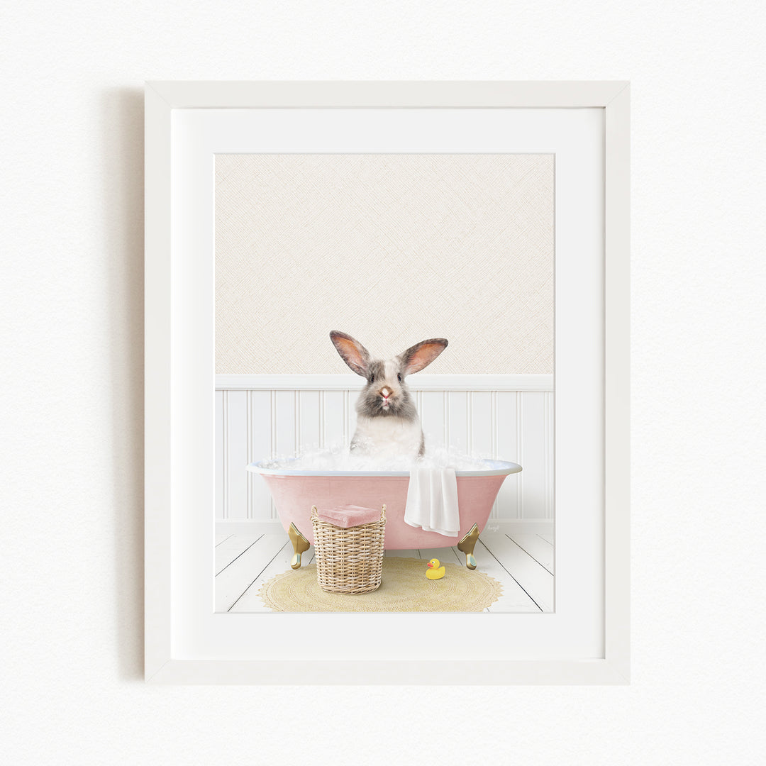 A fluffy white rabbit sits in a pink bathtub filled with bubbles, surrounded by a yellow rubber duck and a basket.