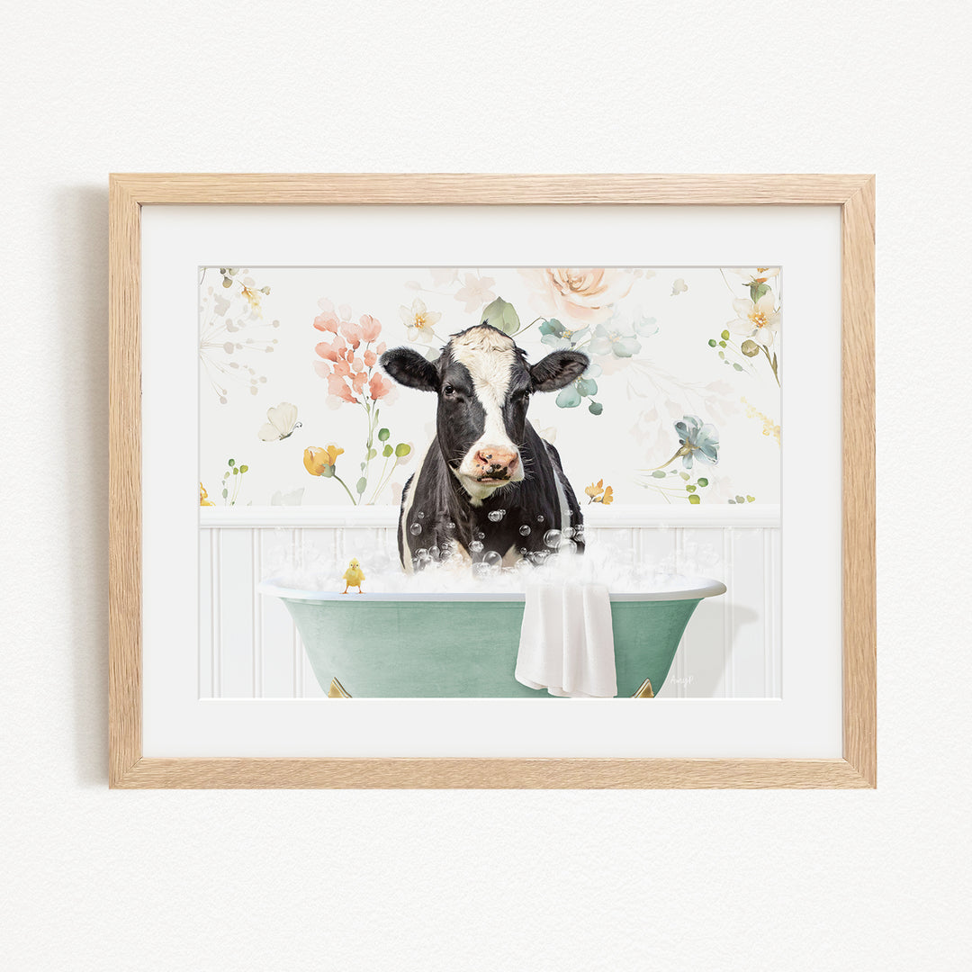 A black and white cow is sitting in a green bathtub filled with bubbles, surrounded by a floral background.