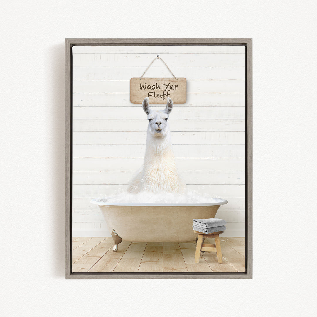 A white llama sitting in a bathtub, with a wooden sign above it that says "Wash Yer Fluff".