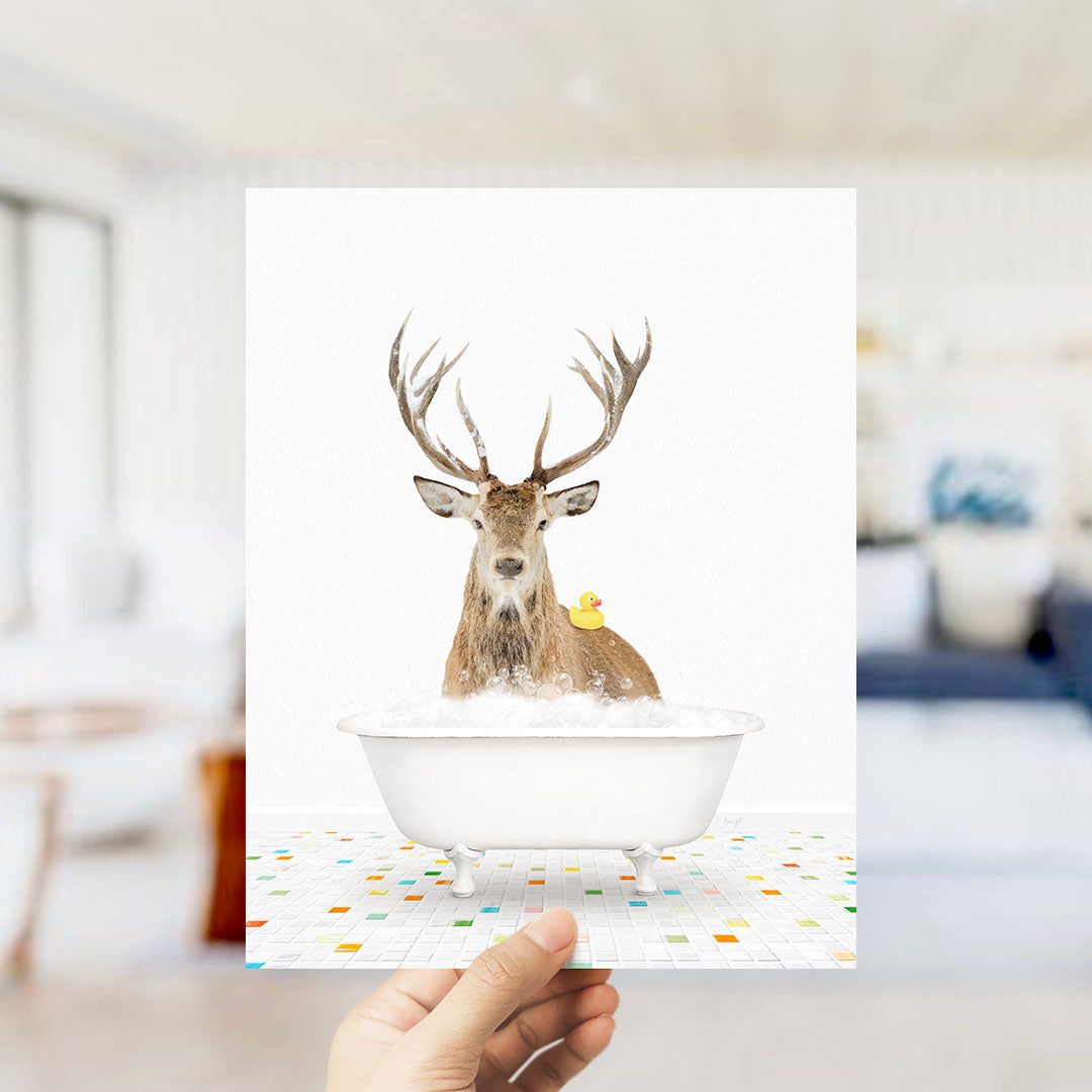 A deer with antlers is sitting in a bathtub filled with bubbles, with a yellow rubber duck floating on the water.