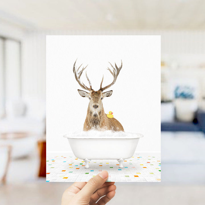 A deer with antlers is sitting in a bathtub filled with bubbles, with a yellow rubber duck floating on the water.