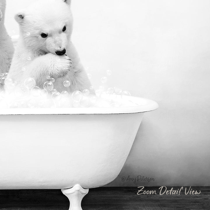 A polar bear cub sitting in a white bathtub filled with bubbles, appearing to be enjoying a bath.