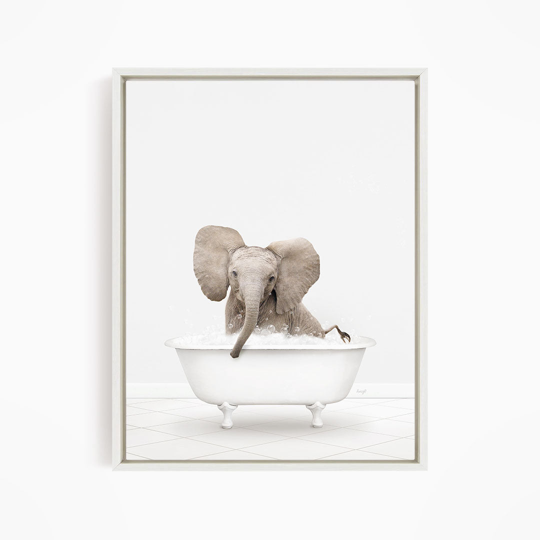 A baby elephant sitting in a white bathtub filled with water, with its trunk submerged in the water.