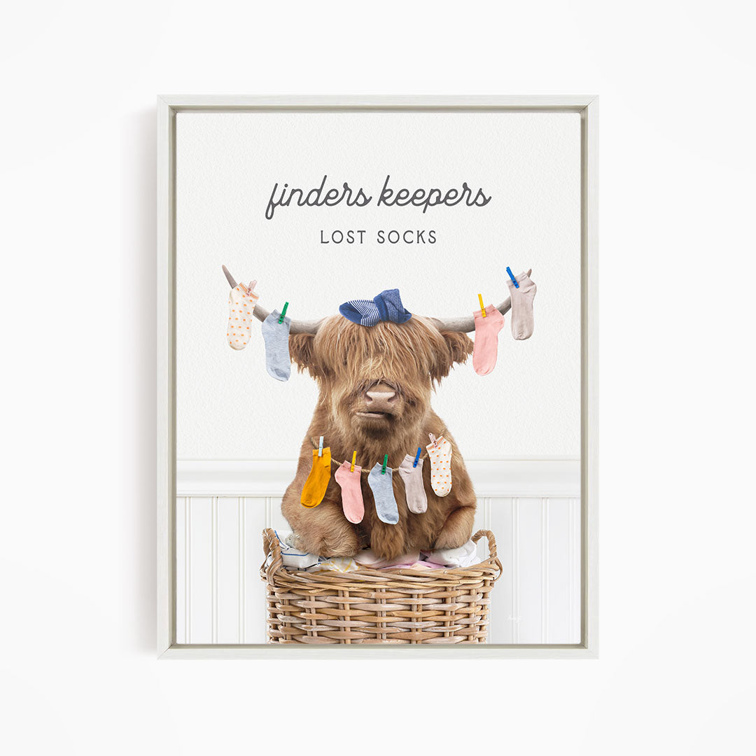 A brown cow sitting in a wicker basket filled with colorful socks, with the text "finders keepers" and "lost socks" displayed above the image.