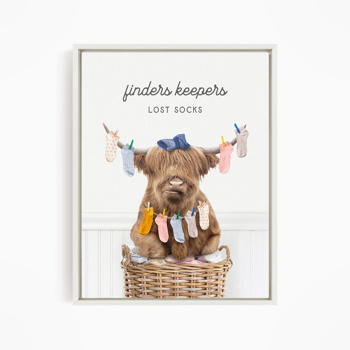 A brown cow sitting in a wicker basket filled with colorful socks, with the text "finders keepers" and "lost socks" displayed above the image.