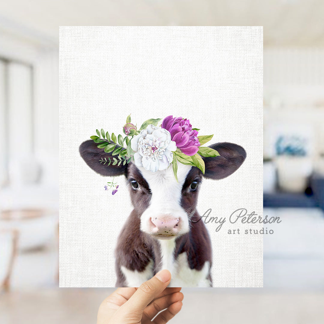 a hand holding up a card with a picture of a cow wearing a flower crown