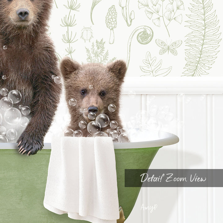 A baby bear sitting in a bathtub filled with bubbles, with a towel draped over the side of the tub.