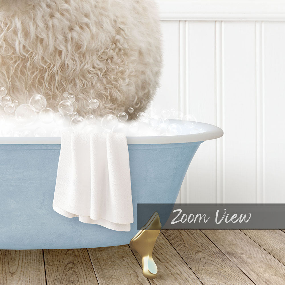 A fluffy white dog is sitting in a blue bathtub filled with bubbles, with a towel draped over the side and a gold bathtub stopper visible.