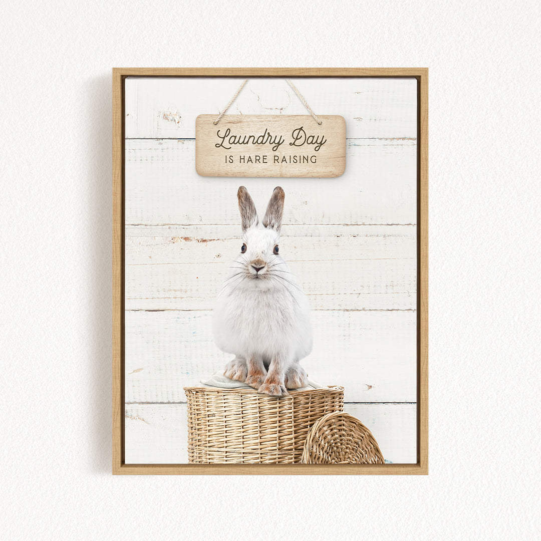 A white rabbit sitting in a wicker basket, with a wooden sign above that says "Laundry Day is Hard Raising".