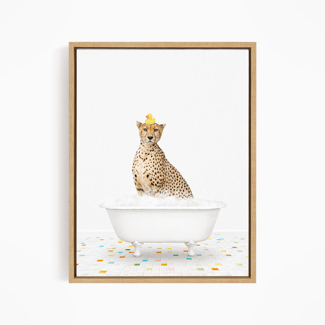 A cheetah sitting in a white bathtub filled with bubbles, wearing a yellow rubber duck on its head.