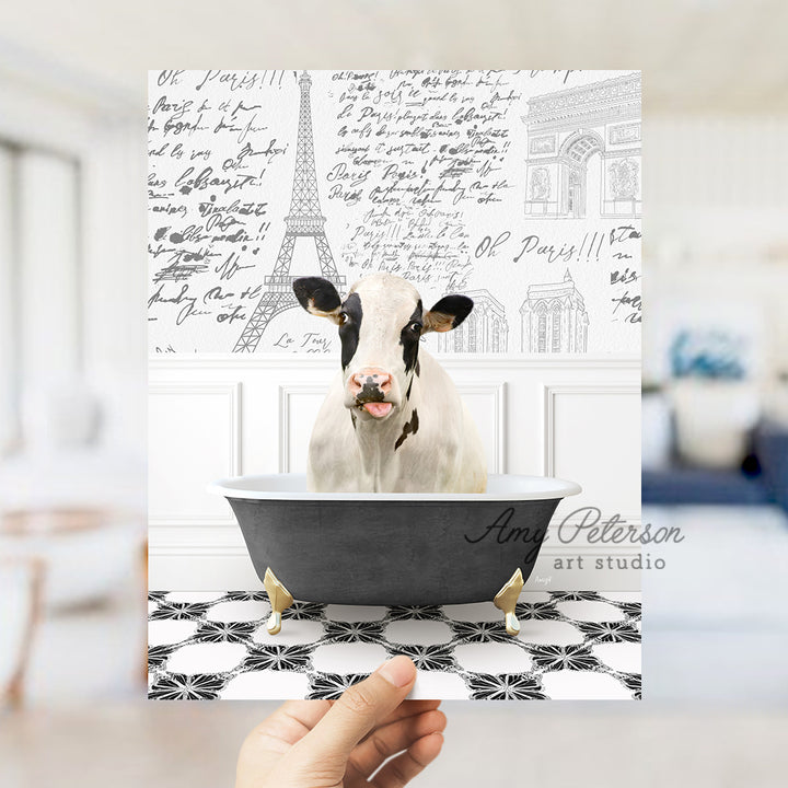 a hand holding a card with a cow in a bathtub