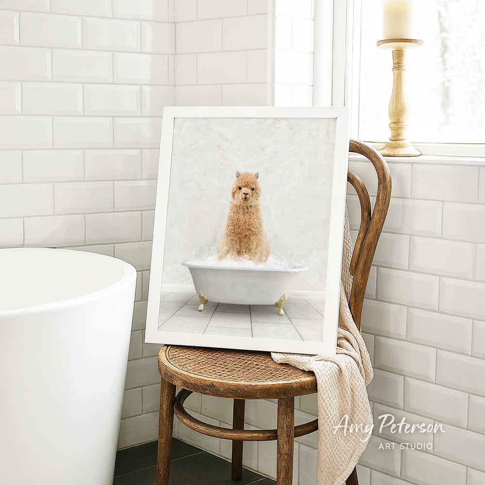 A framed image of a small dog sitting in a bathtub, surrounded by white tiles, is displayed on a wooden chair in a bathroom setting.