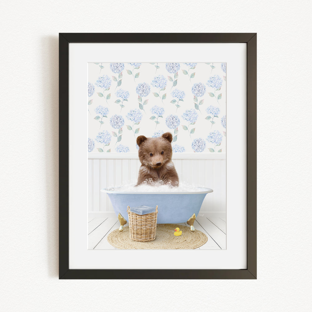 A brown bear sitting in a blue bathtub filled with bubbles, surrounded by a floral patterned wall and a basket of rubber ducks.