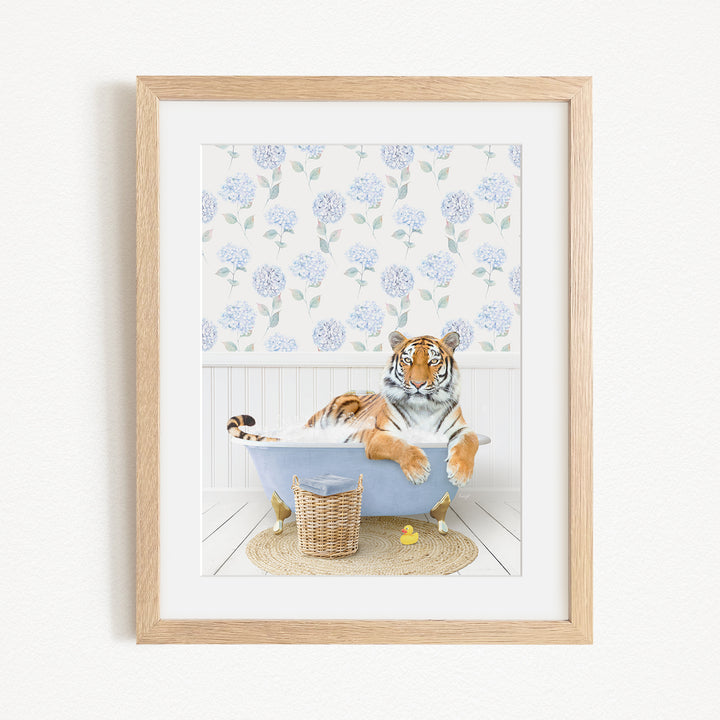 A tiger is sitting in a bathtub filled with water, surrounded by blue flowers and yellow rubber ducks.