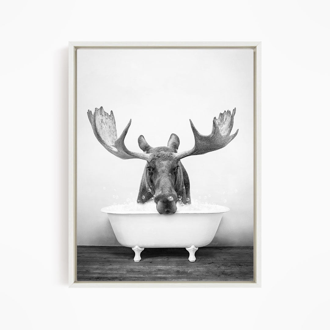 A moose with large antlers is sitting in a bathtub filled with water, creating a whimsical and humorous scene.