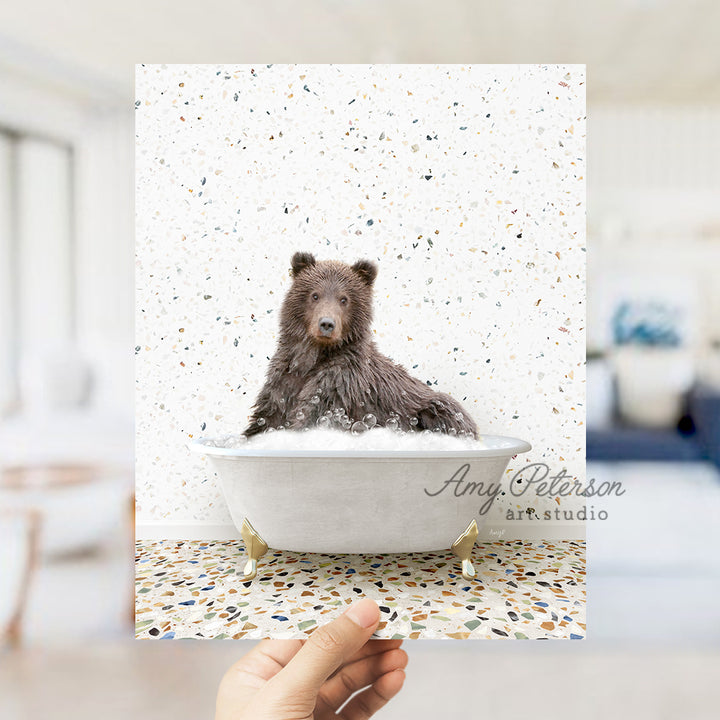 a hand holding up a card with a bear in a bathtub