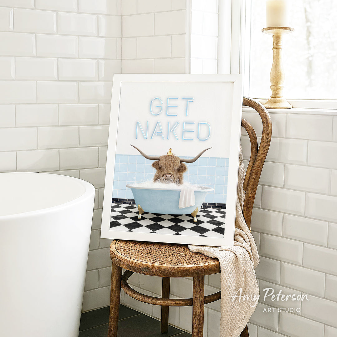 a framed print of a cartoon image of a cow sitting in a bathtub, with the text "GET NAKED" displayed on the print.