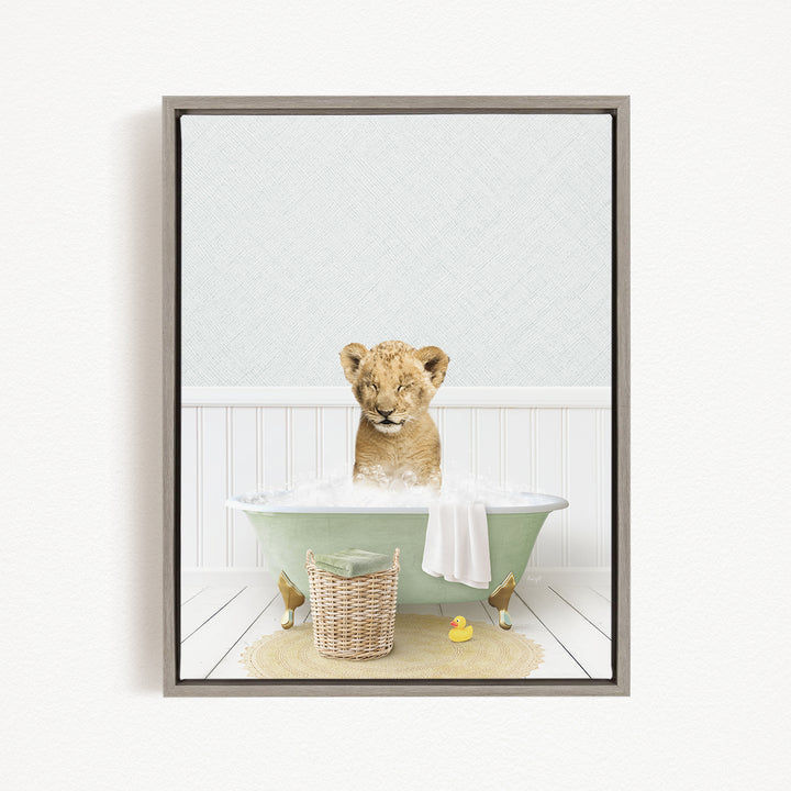 A young lion cub sitting in a green bathtub filled with water, surrounded by a basket of toys and a rubber duck.
