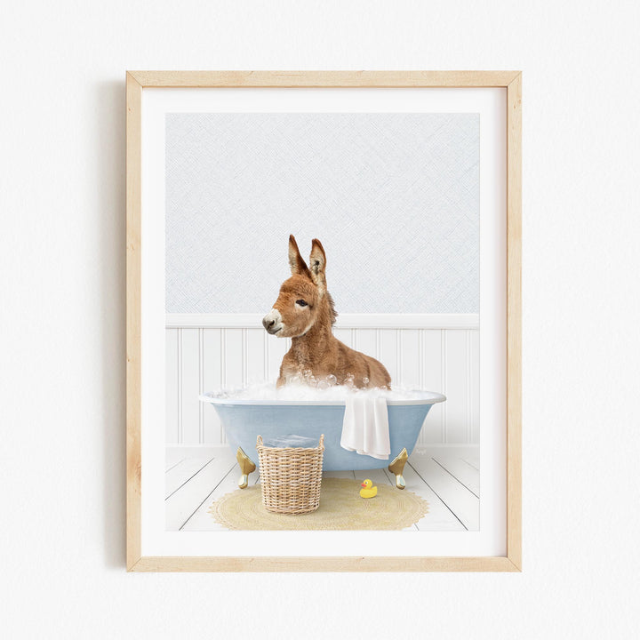 A donkey is sitting in a blue bathtub filled with water, surrounded by rubber ducks.