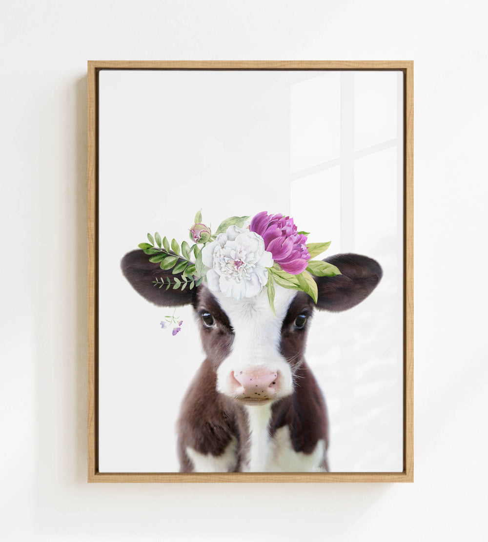 A framed image of a cow wearing a floral crown on its head.