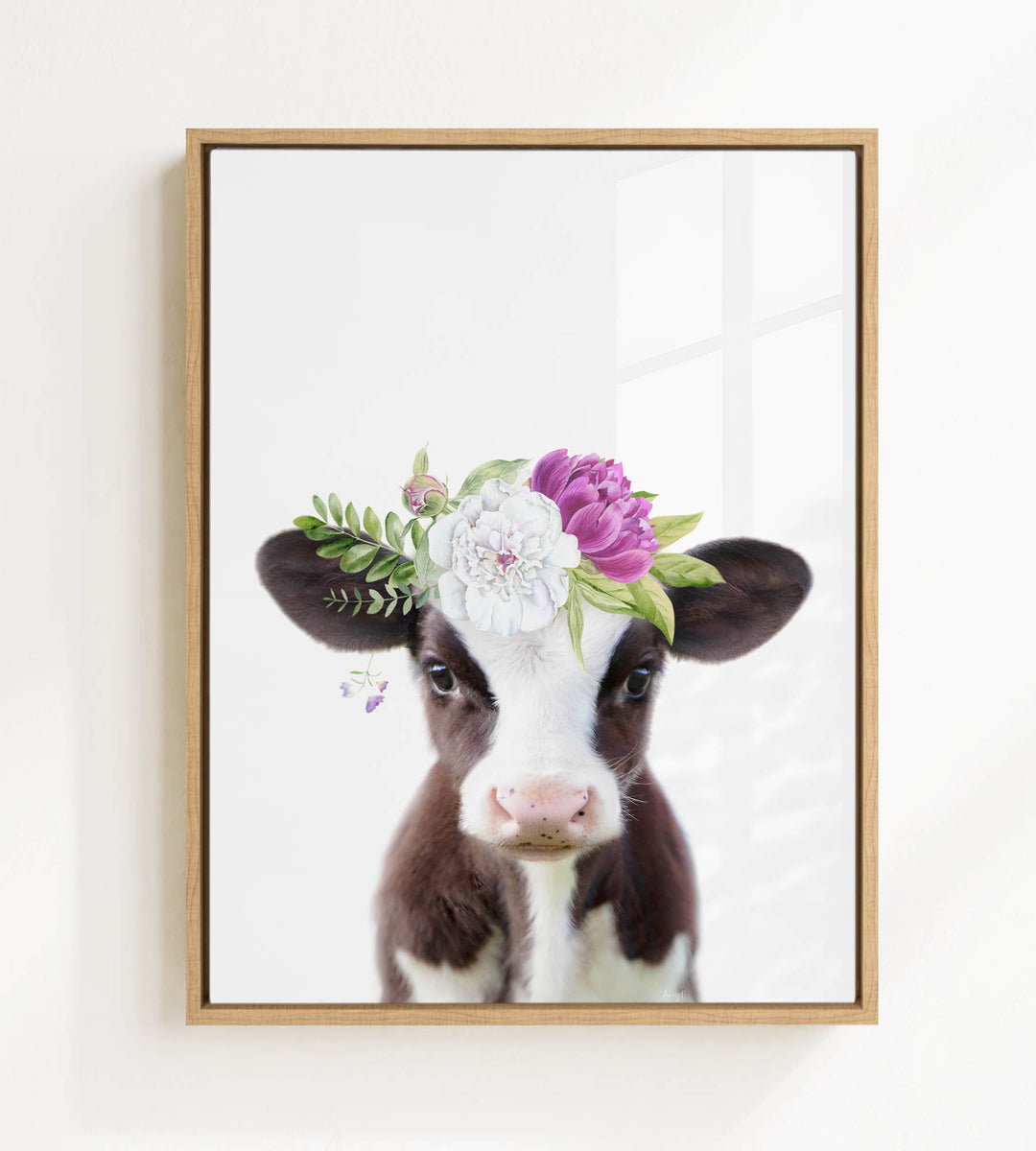 A framed image of a cow wearing a floral crown on its head.
