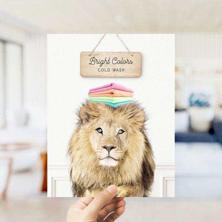 A hand is holding up a framed image of a lion with a sign above it that says "Bright Colors Cold Wash".