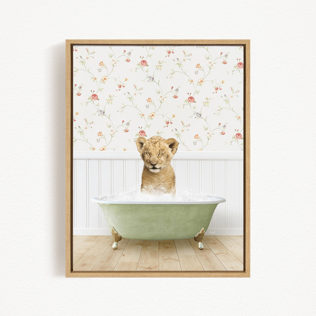 A young lion cub sitting in a green bathtub filled with water, with a floral wallpaper in the background.