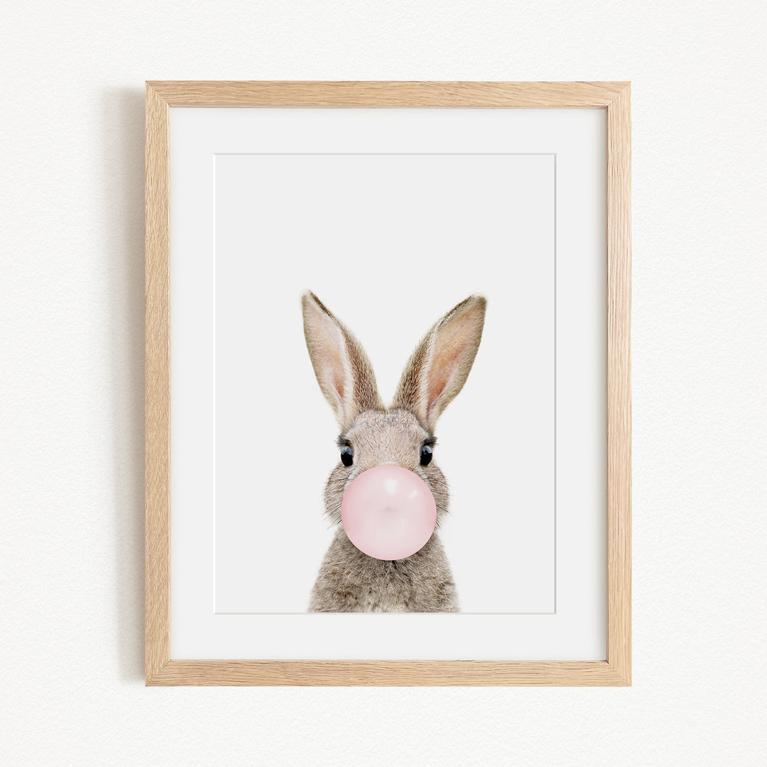 A framed image of a rabbit blowing a bubble with a pink bubblegum bubble.