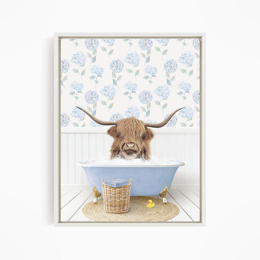 A brown cow with long horns is sitting in a blue bathtub filled with water, surrounded by a wicker basket and yellow rubber ducks.