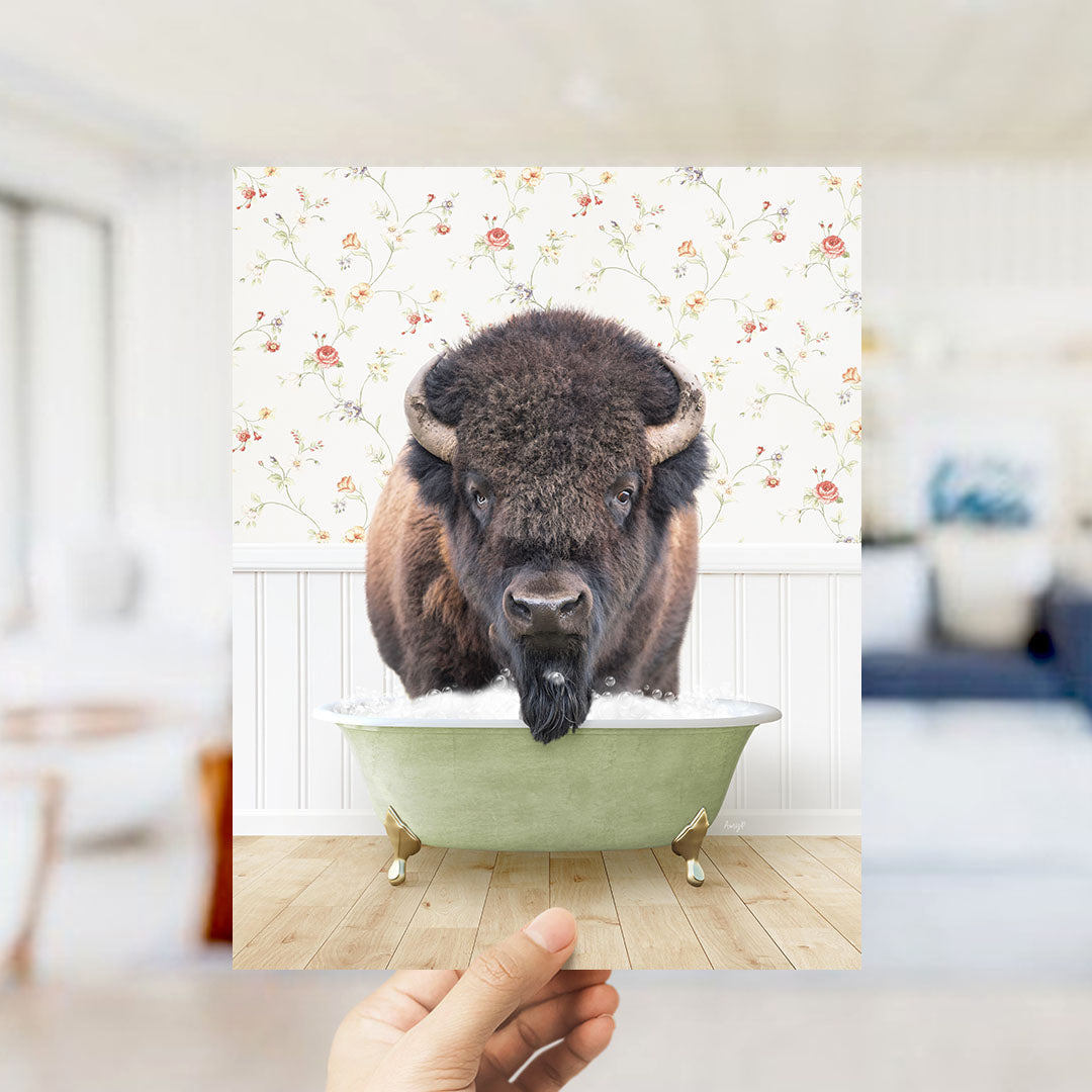 A bison with a long beard is sitting in a green bathtub, surrounded by a floral wallpaper.