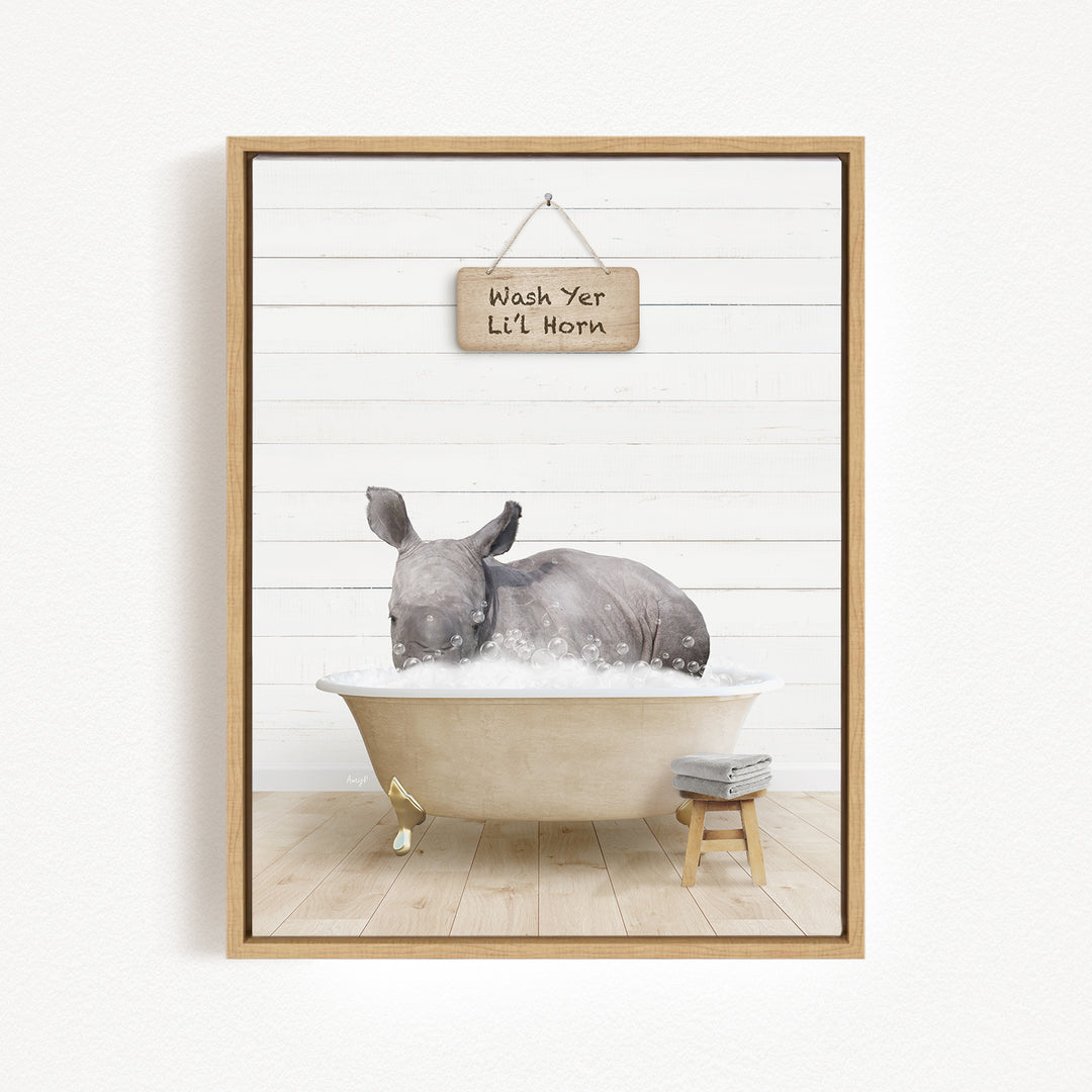 A rhinoceros is sitting in a bathtub filled with water, with a sign above it that says "Wash Yer L'l Horn".