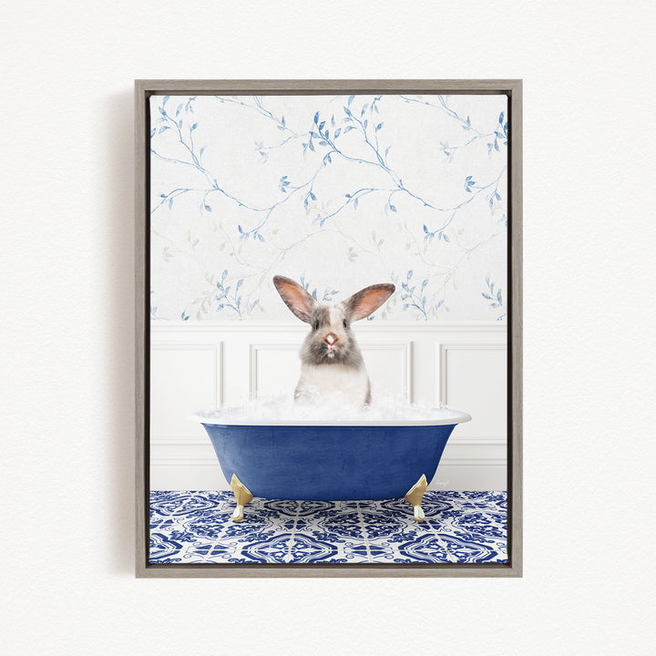 A white and gray rabbit sitting in a blue bathtub filled with water, with a patterned tile floor and a floral wallpaper in the background.