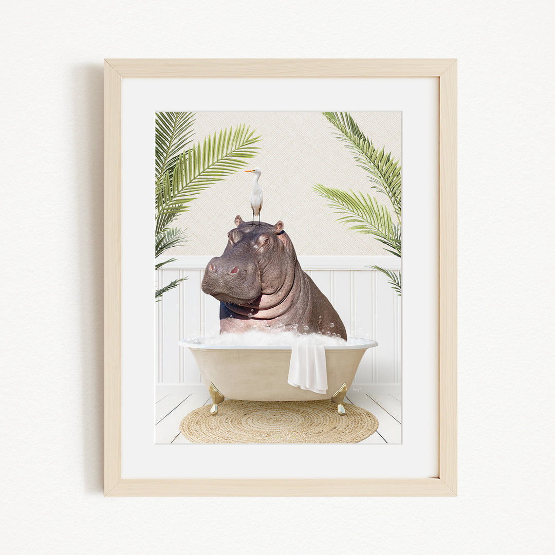 A framed image depicting a hippopotamus sitting in a bathtub, with a bird perched on its head.