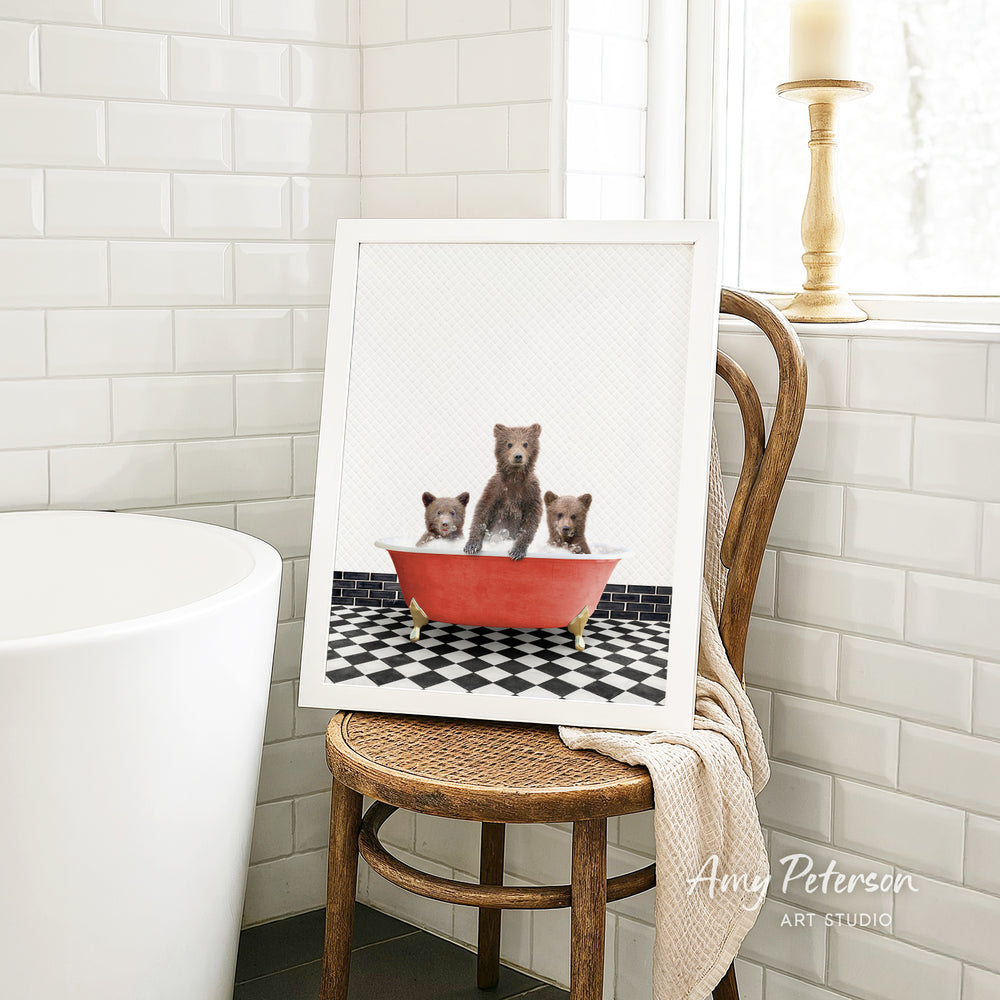 A framed image of three bears sitting in a red bathtub, with a black and white checkered floor in the background.