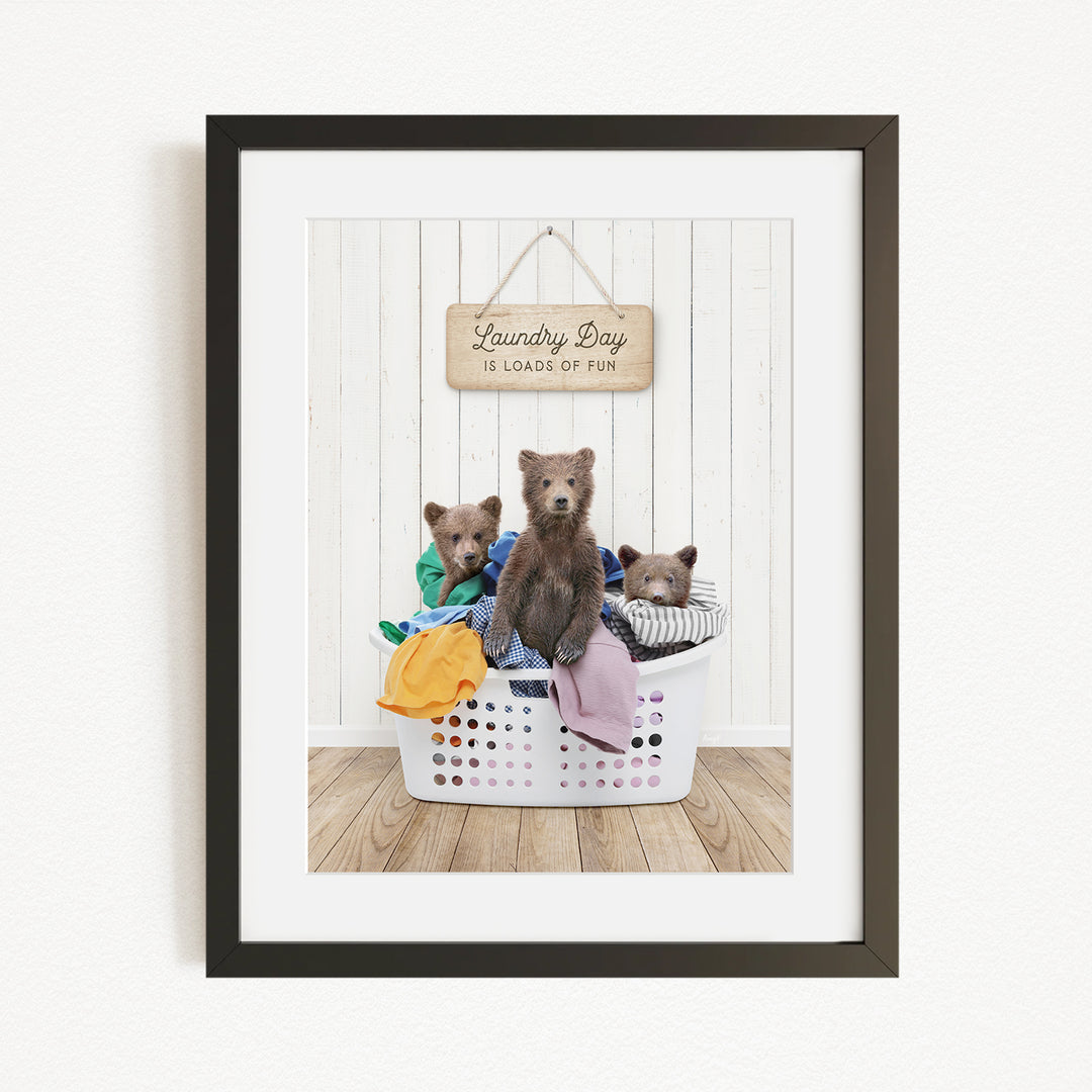 A framed image depicting three bears sitting in a laundry basket, with a sign above them that reads "Laundry Day is loads of fun".