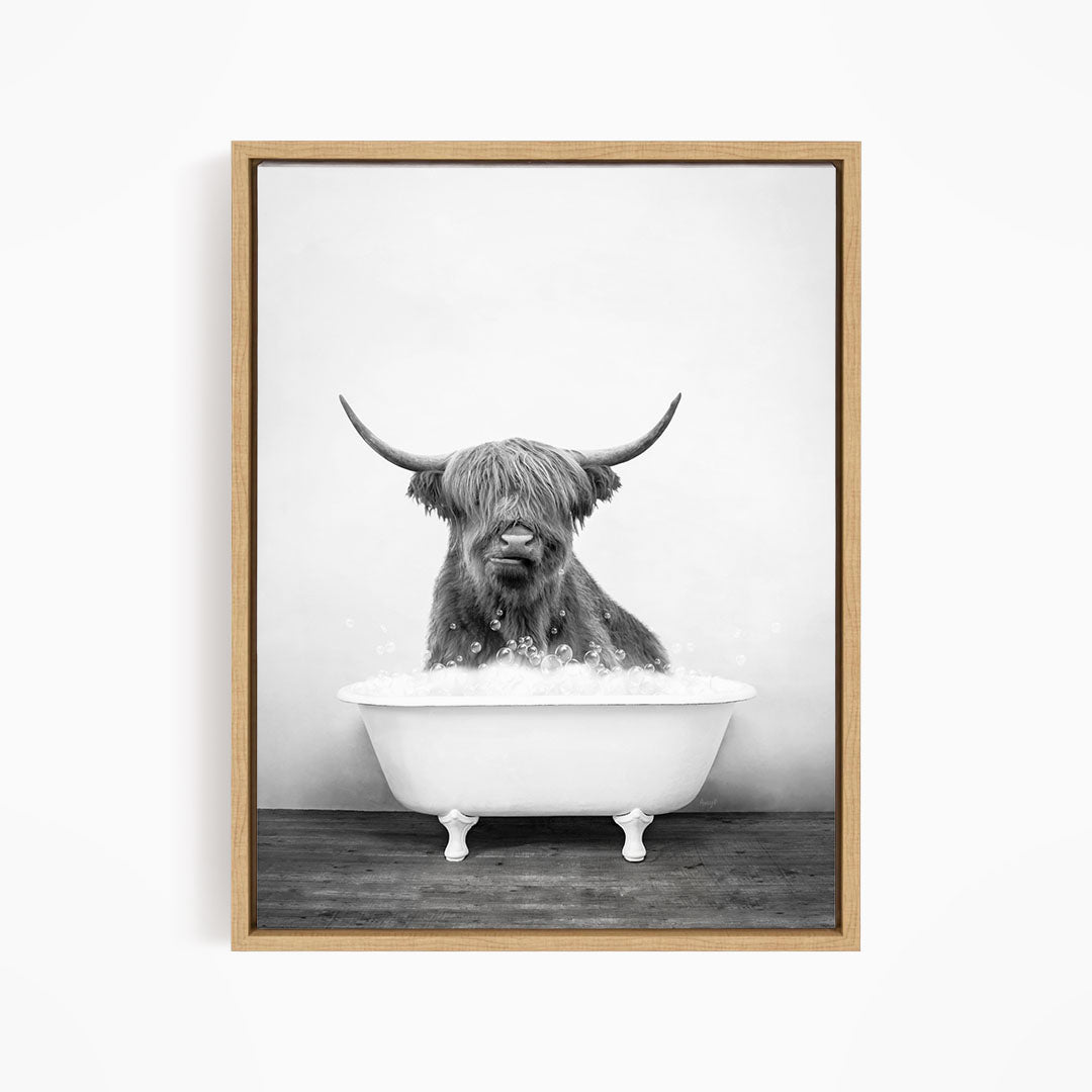 A black and white image of a Highland cow sitting in a bathtub filled with water.