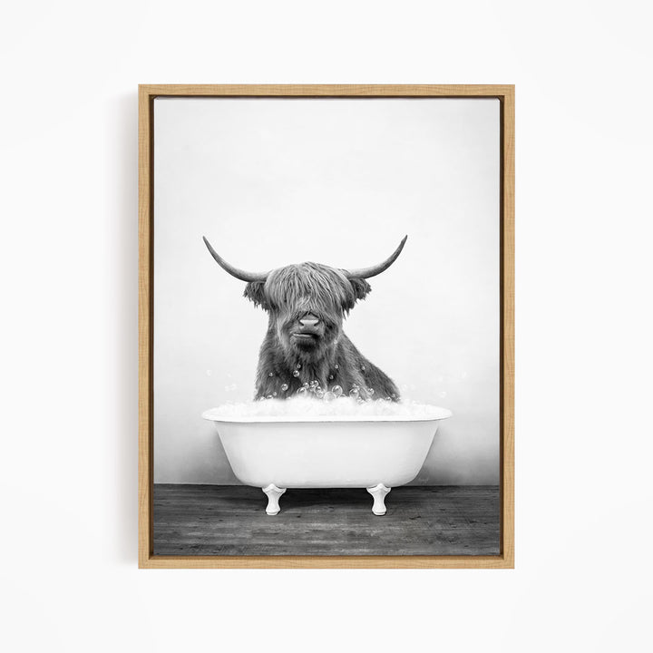 A black and white image of a Highland cow sitting in a bathtub filled with water.