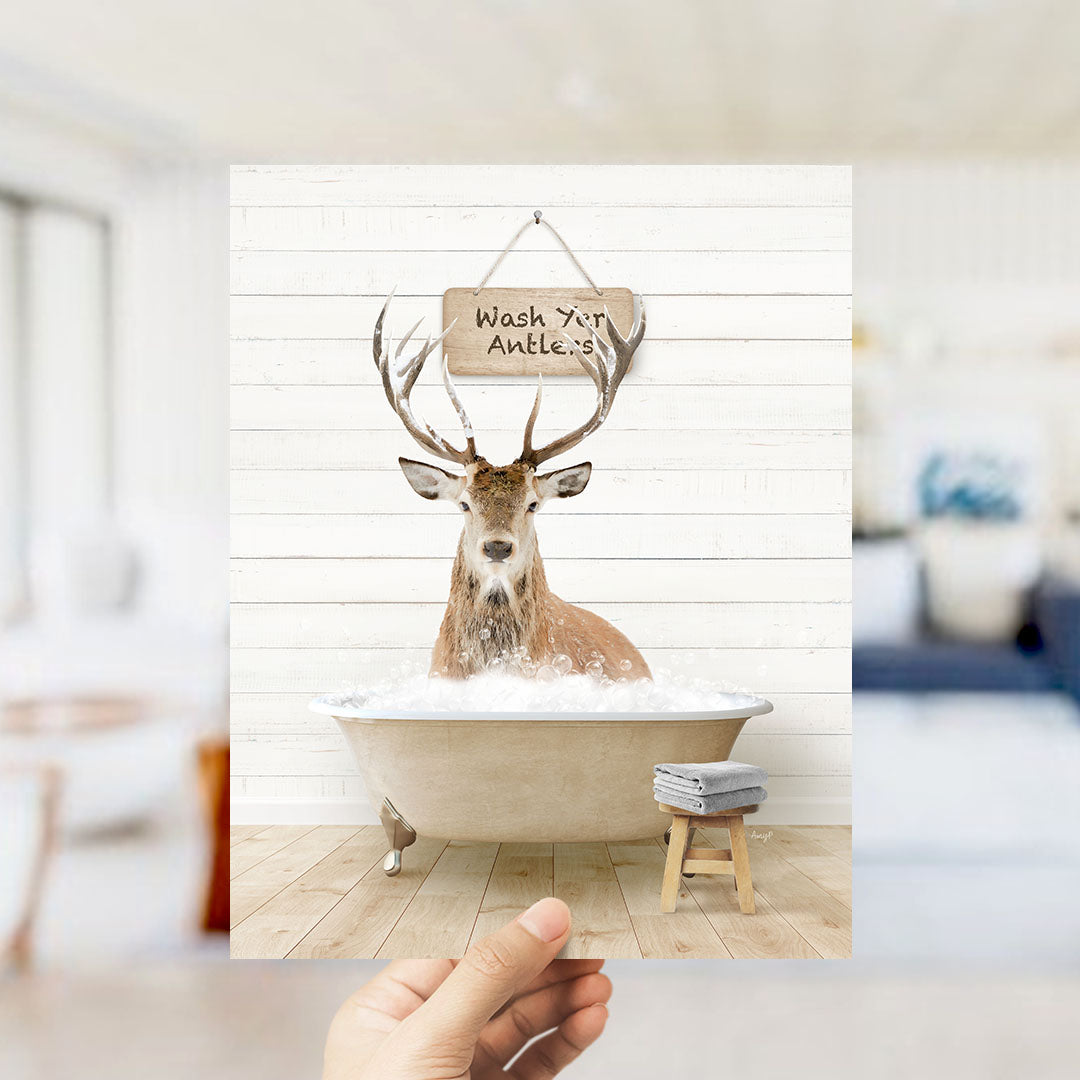 A deer with antlers is sitting in a bathtub filled with water, with a sign above it that says "Wash your antlers".