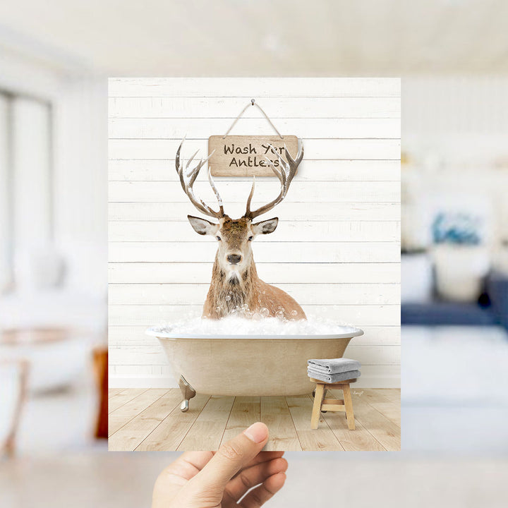 A deer with antlers is sitting in a bathtub filled with water, with a sign above it that says "Wash your antlers".