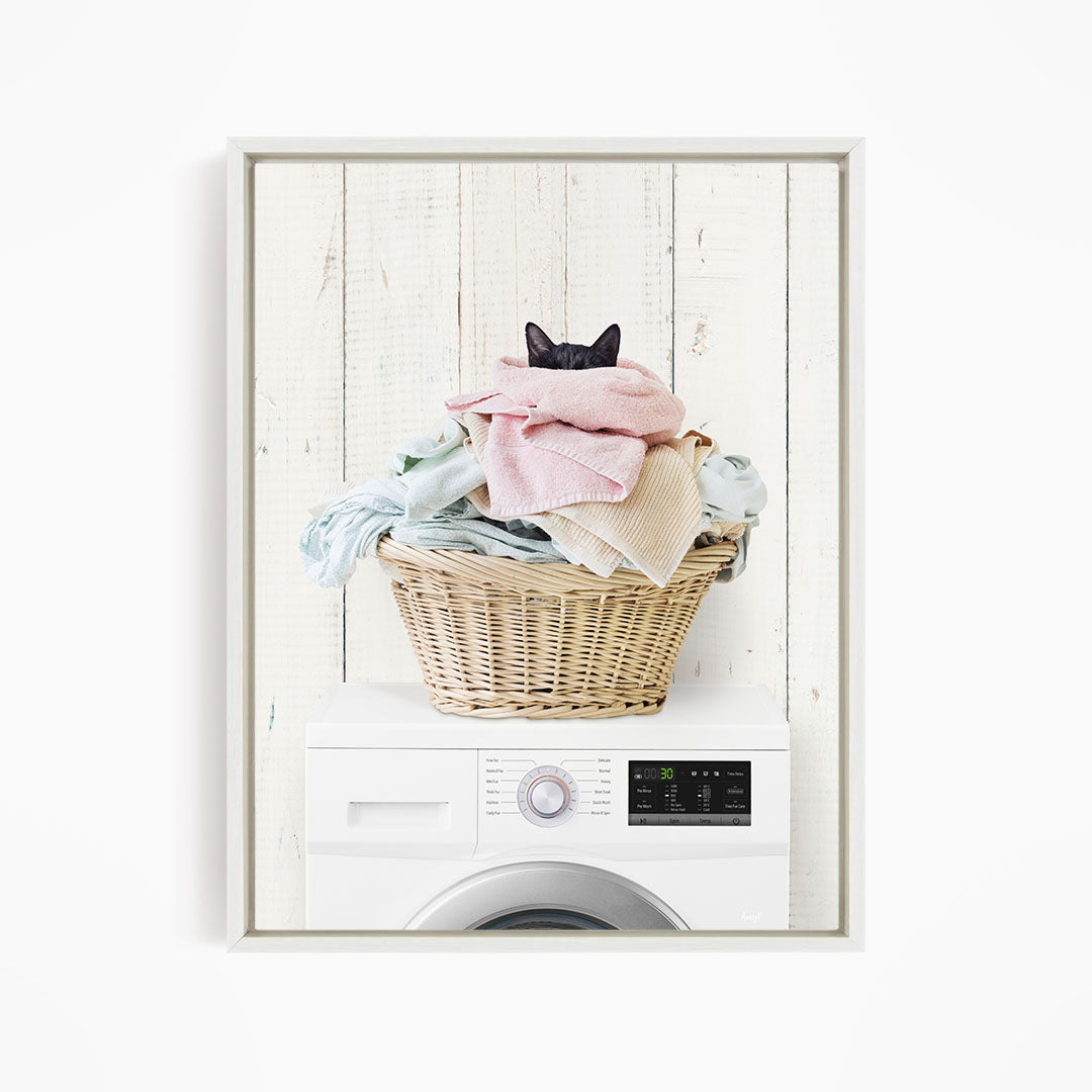 A cat is sitting on top of a basket filled with laundry, which is placed on top of a washing machine.
