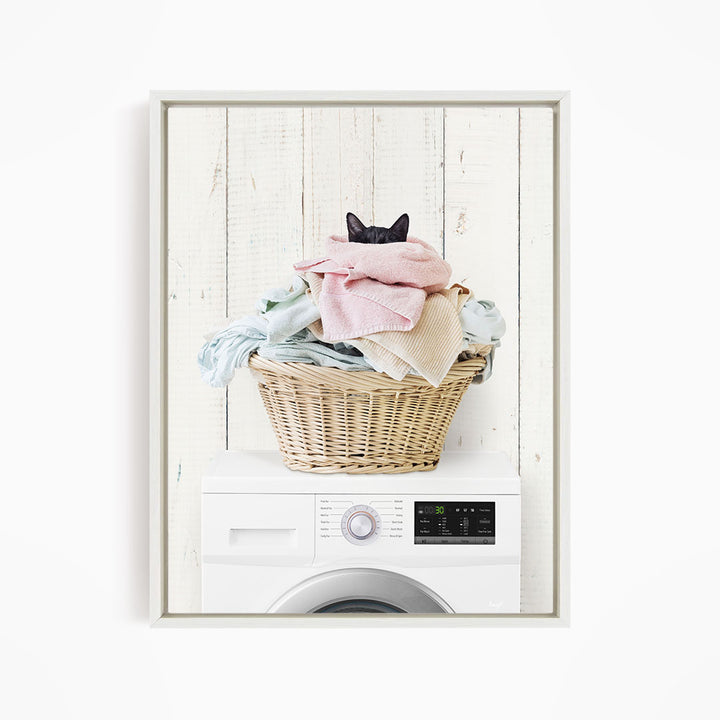 A cat is sitting on top of a basket filled with laundry, which is placed on top of a washing machine.