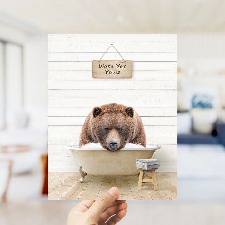 A brown bear sitting in a bathtub with a sign that says "Wash Your Paws" above it.