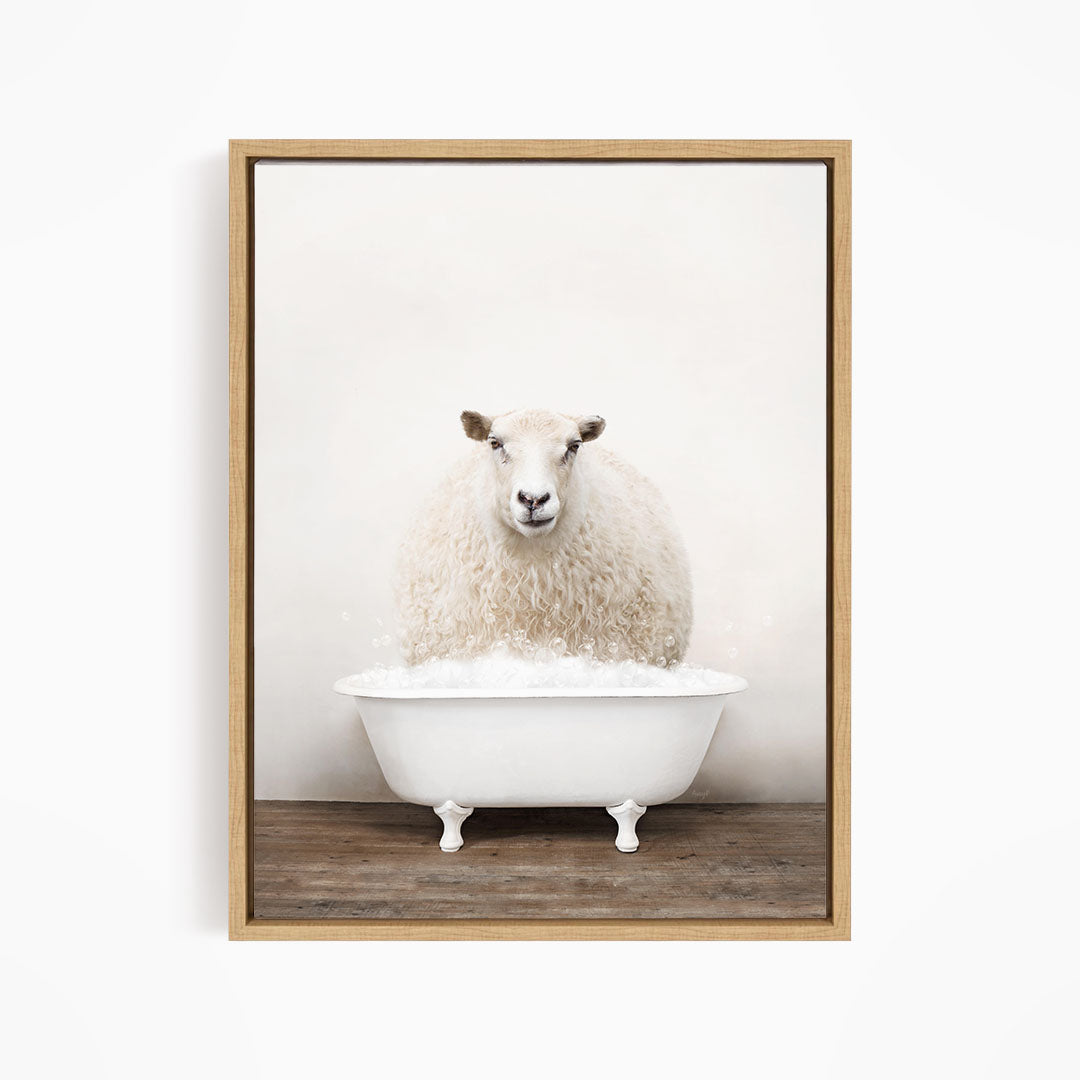A fluffy white sheep sits in a white bathtub filled with bubbles, looking directly at the camera.