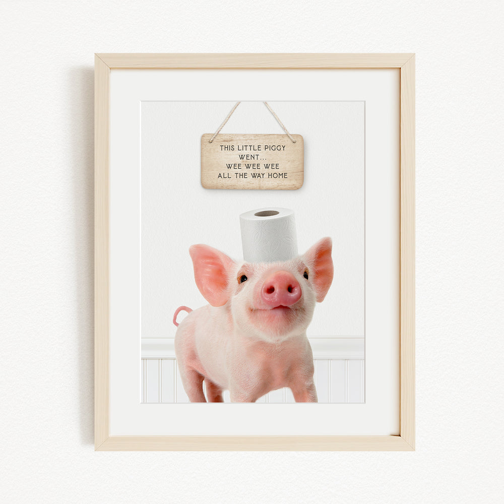 A framed image of a pig standing on a white surface, with a wooden sign above it that reads "This little piggy went weee weee all the way home".