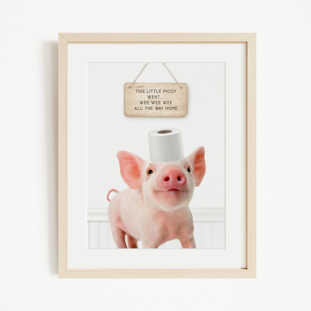 A framed image of a pig standing on a white surface, with a wooden sign above it that reads "This little piggy went weee weee all the way home".