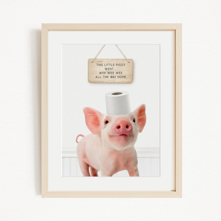 A framed image of a pig standing on a white surface, with a wooden sign above it that reads "This little piggy went weee weee all the way home".