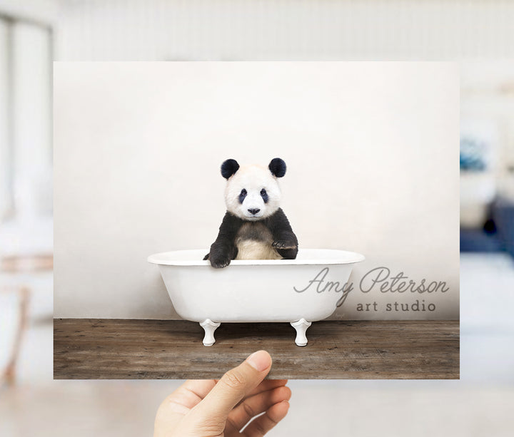 a hand holding a photo of a panda bear in a bathtub