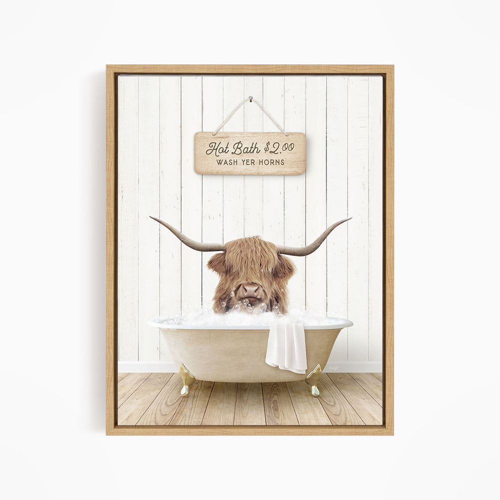 A framed image depicting a horned animal, likely a yak or a similar animal, sitting in a bathtub filled with water, with a sign above the tub stating "Hot Bath $2.00 Wash Your Horns".