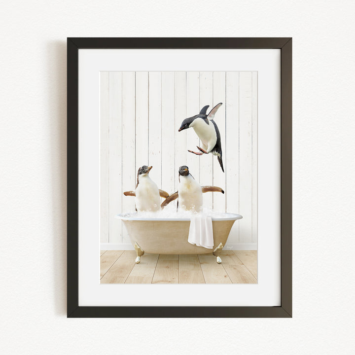 A framed image depicting two penguins sitting in a bathtub, with one penguin flying towards the other.