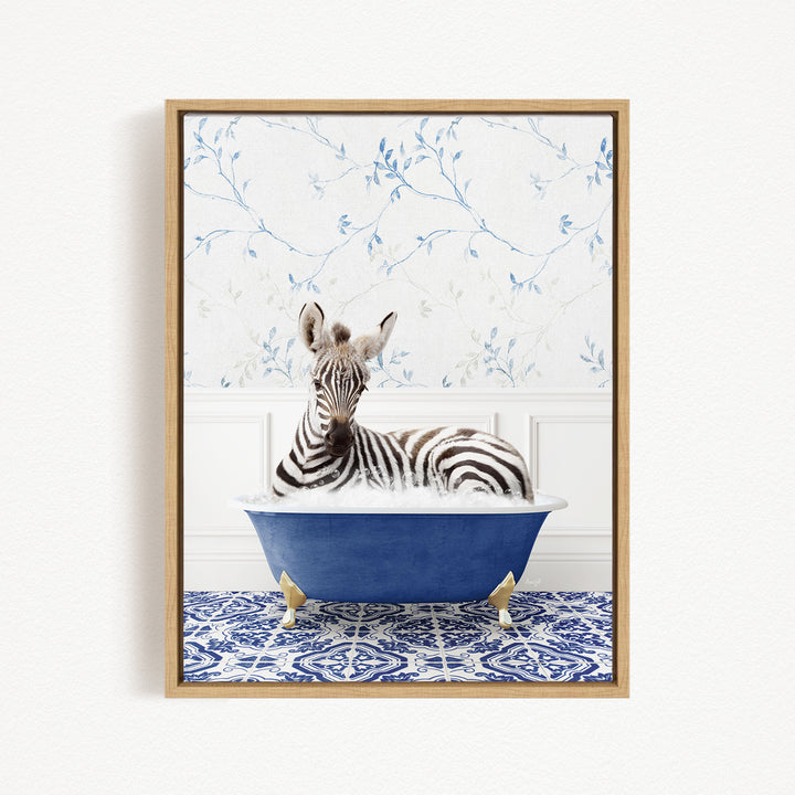 A zebra is sitting in a blue bathtub, surrounded by a patterned blue and white rug.